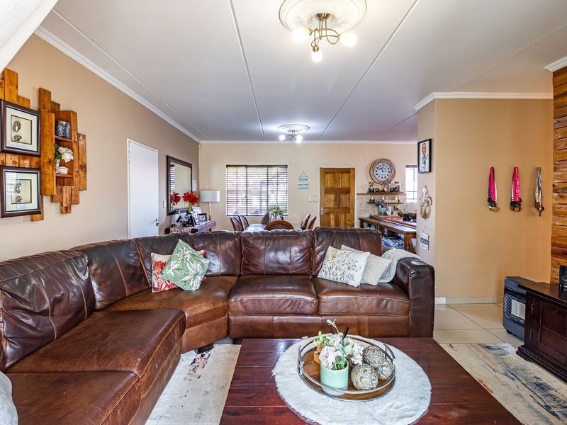 Spacious open-plan living and dining area featuring tiled flooring, decorative ceiling roses, and a rustic timber-clad feature wall.