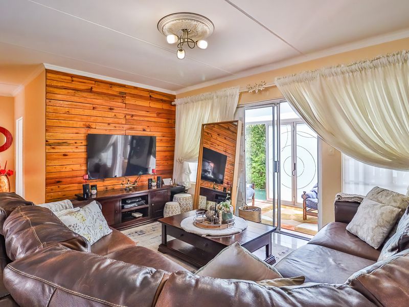 A cozy living room featuring a wood-paneled accent wall, tiled flooring, and sliding glass doors that provide direct access to the outdoor patio area.
