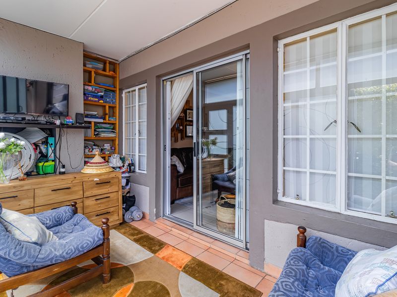 A covered patio area featuring tiled flooring, built-in shelving, and sliding glass doors providing access to the interior living space.