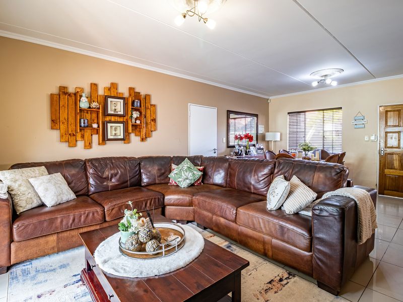 Spacious open-plan living and dining area featuring tiled flooring, neutral wall tones, and natural light through venetian blinds.