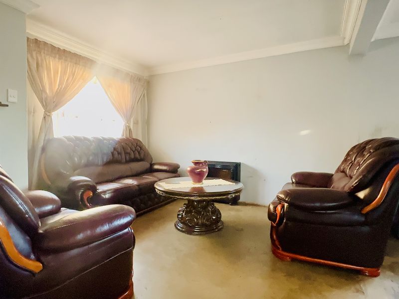 A living room featuring neutral walls, coving, and carpeted flooring, offering a blank canvas for potential interior updates and modernization.