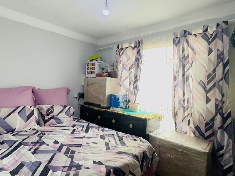 A standard bedroom featuring neutral wall finishes and a window with curtain treatments.
