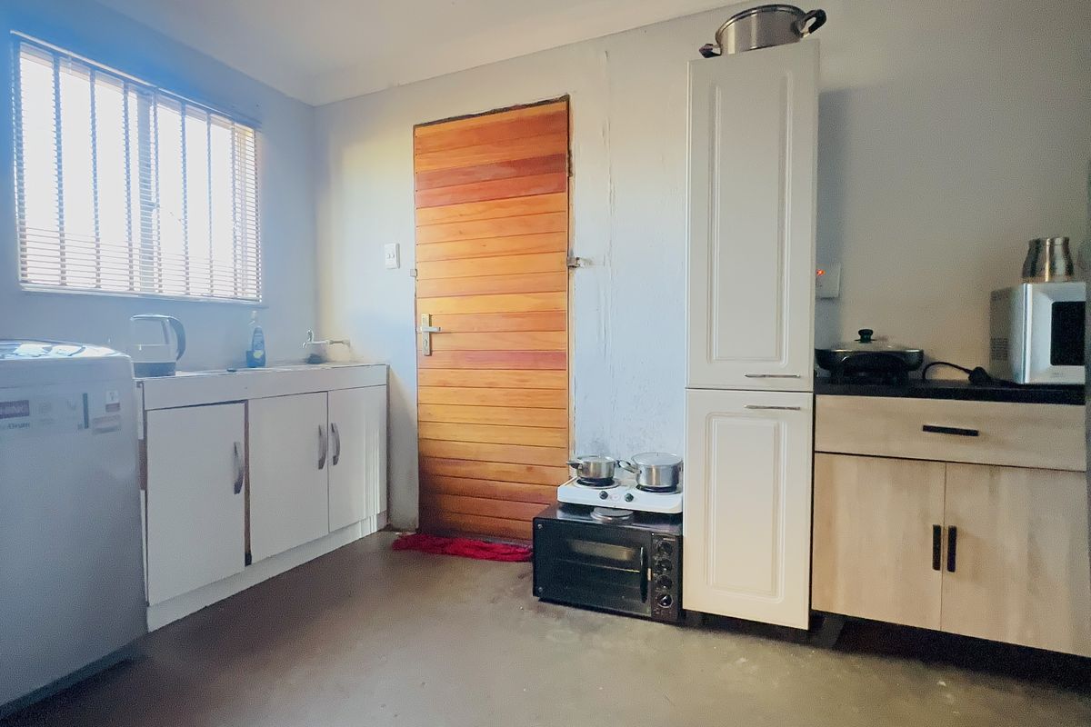 A functional kitchen area featuring built-in cabinetry, a sink, and a wooden door, with potential for cosmetic updates to improve the overall aesthetic.
