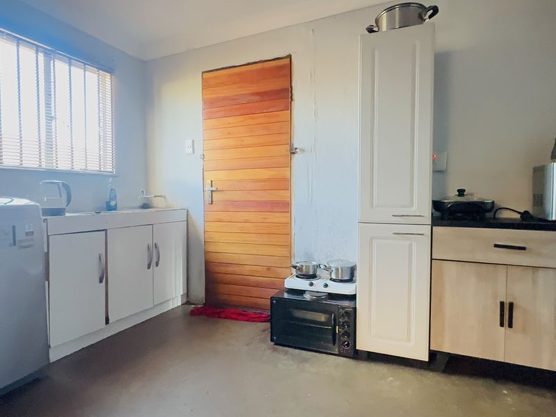 A functional kitchen area featuring built-in cabinetry, a sink, and a wooden door, with potential for cosmetic updates to improve the overall aesthetic.