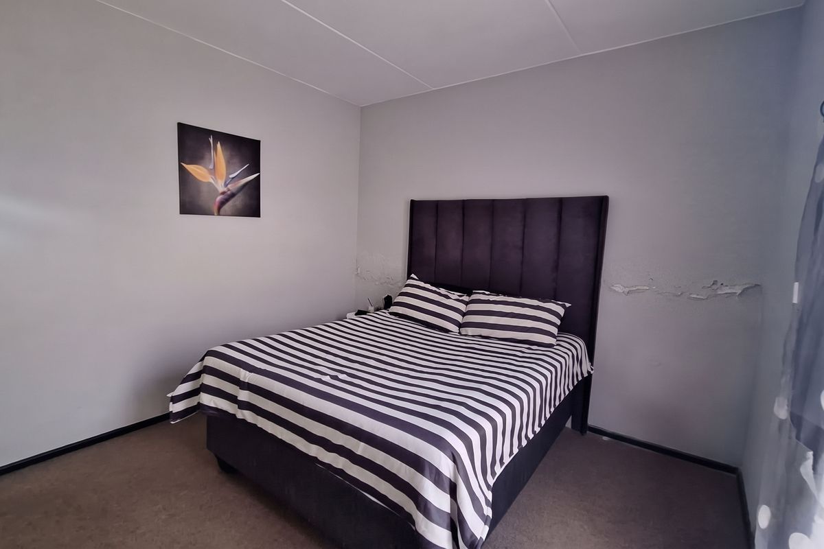 A bedroom featuring carpeted flooring and visible wall surface damage requiring repair and repainting.