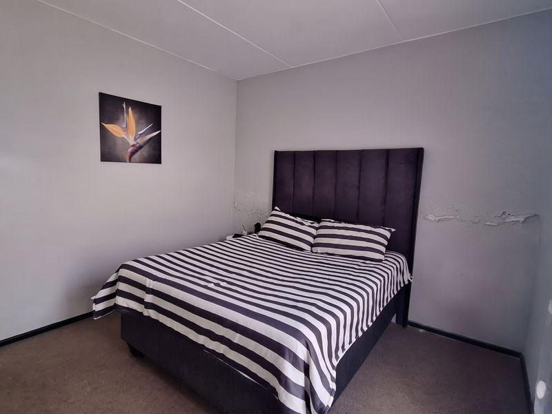 A bedroom featuring carpeted flooring and visible wall surface damage requiring repair and repainting.