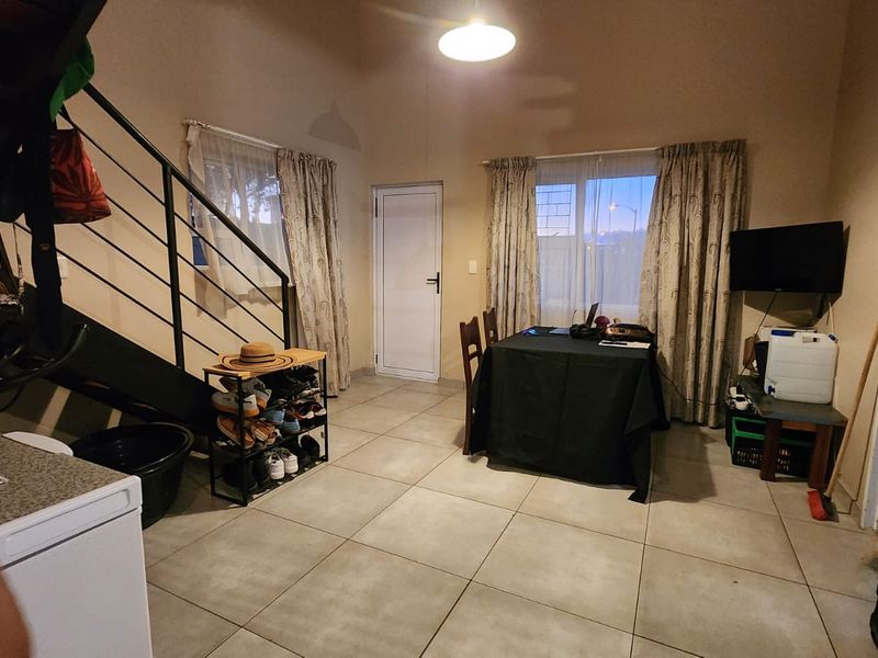 Open plan living area featuring tiled flooring and a metal staircase leading to the upper level.