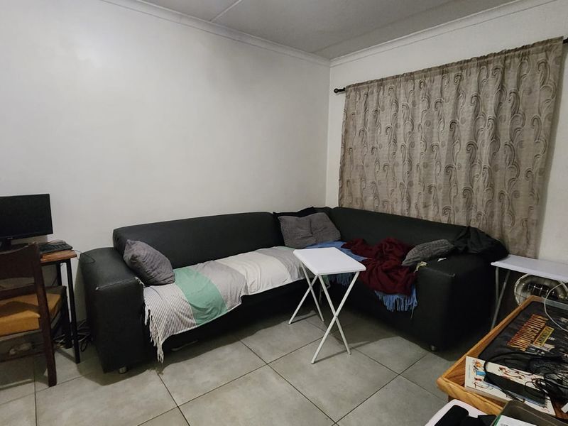 A living room area featuring tiled flooring and neutral wall finishes, providing a functional space for relaxation.