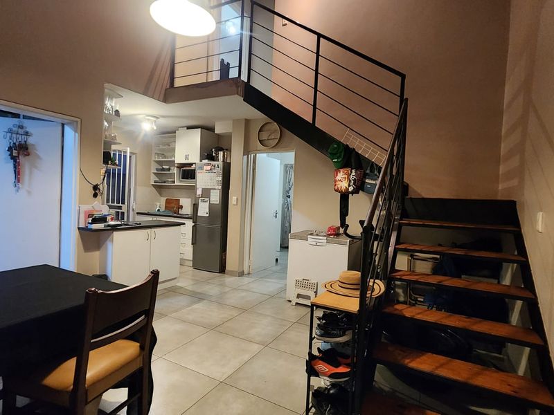 Open plan living and kitchen area featuring tiled flooring and a prominent metal staircase leading to an upper level.