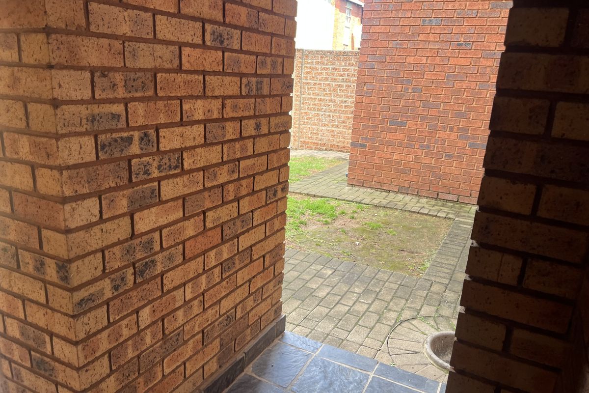 A view of a private rear courtyard featuring face brick walls and paved flooring, providing a functional outdoor space.