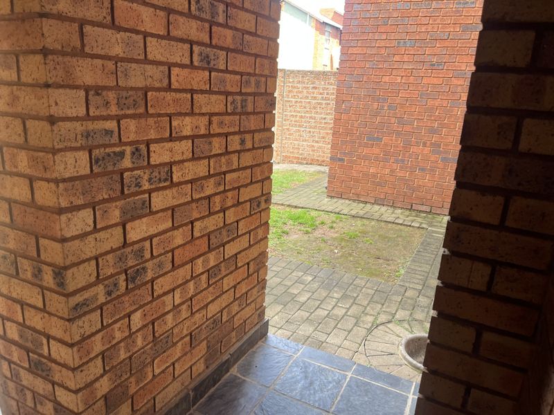 A view of a private rear courtyard featuring face brick walls and paved flooring, providing a functional outdoor space.