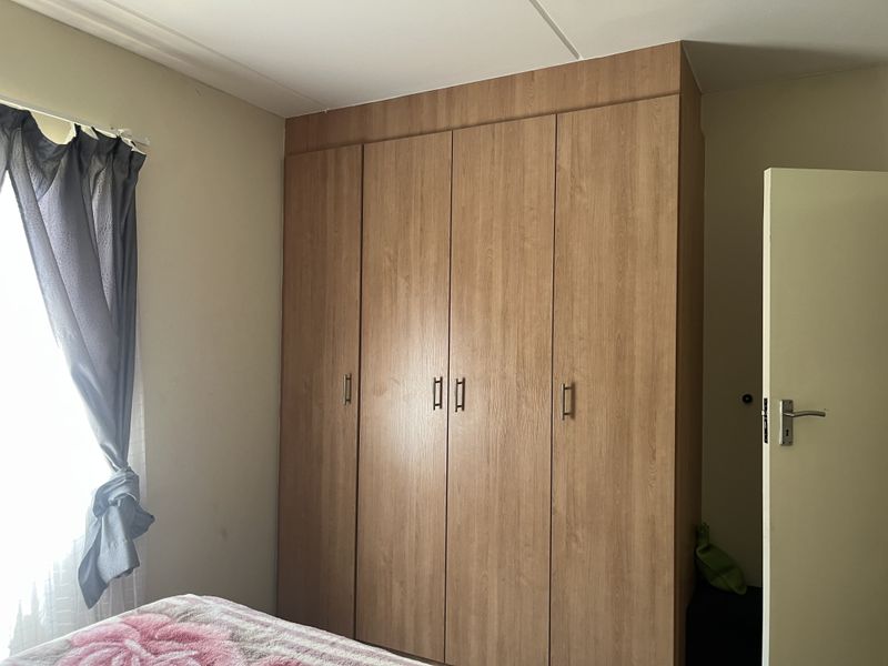 A bedroom featuring a large, wood-finish built-in wardrobe providing ample storage space.
