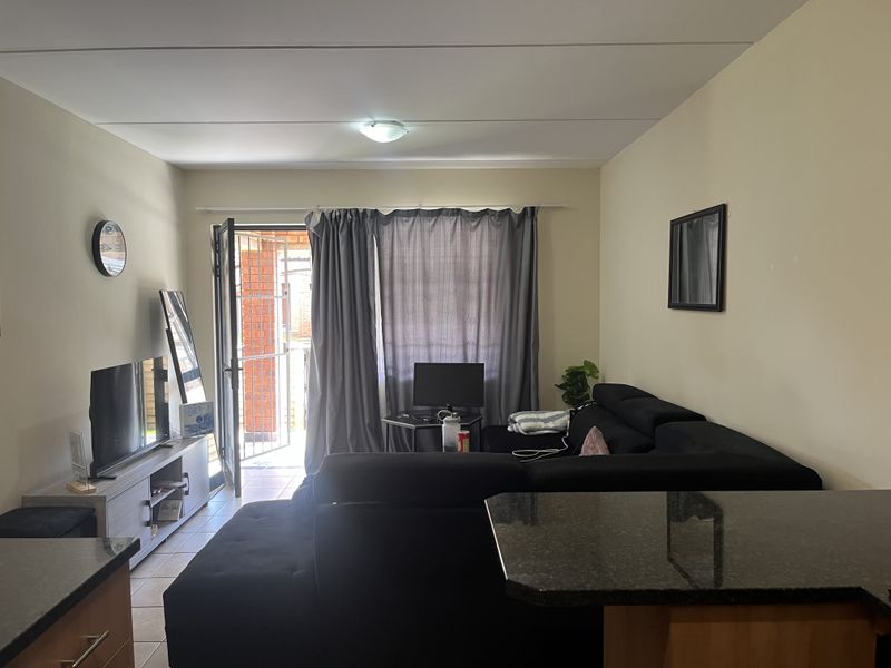 Open plan living area featuring tiled flooring, a granite breakfast bar, and direct access to an outdoor space through a security gate.