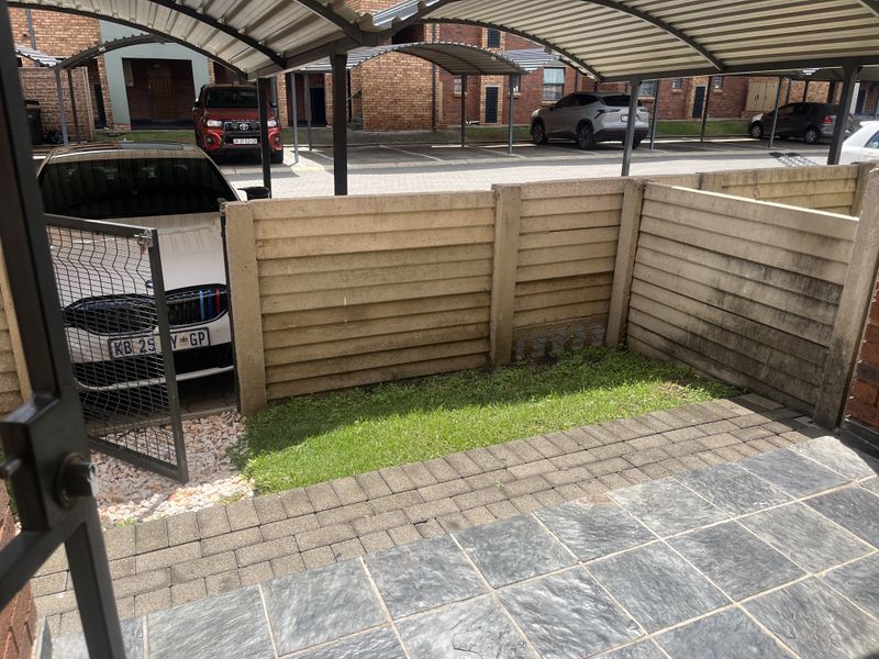A private paved patio area featuring a precast concrete boundary wall and direct access to the complex parking area.