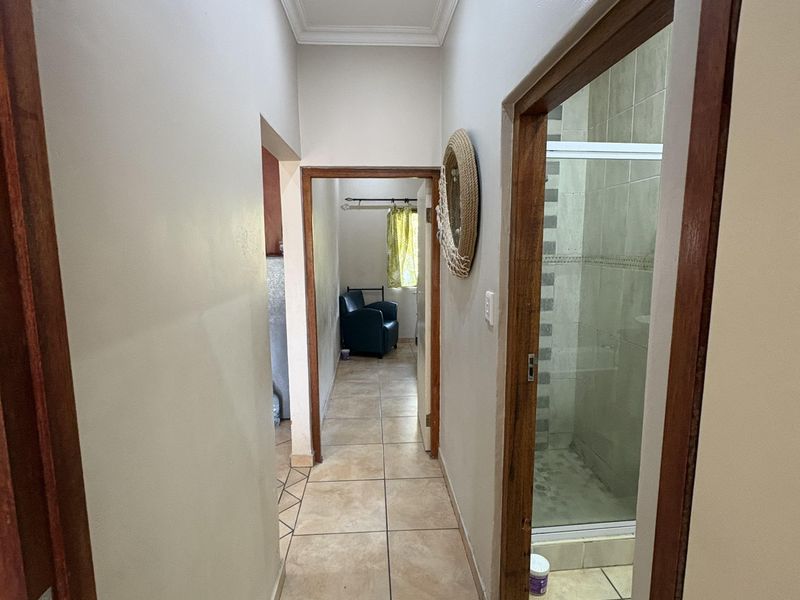 A functional hallway featuring tiled flooring and wooden door frames, providing access to a bathroom and adjacent living space.