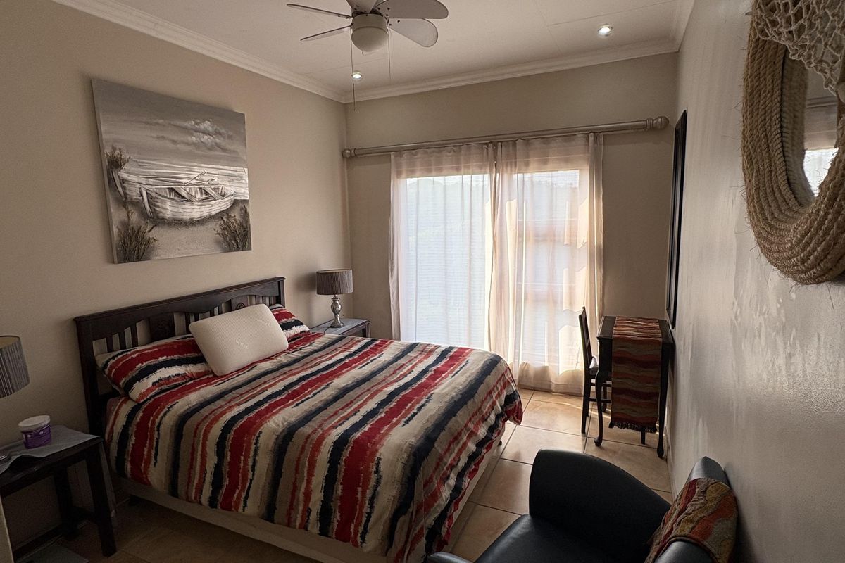 A bedroom featuring tiled flooring, a ceiling fan, and a sliding glass door providing natural light.