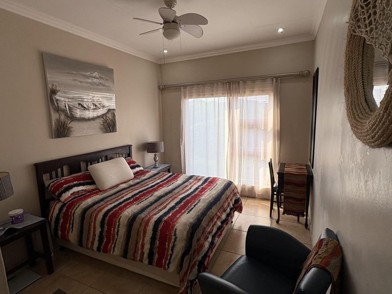 A bedroom featuring tiled flooring, a ceiling fan, and a sliding glass door providing natural light.