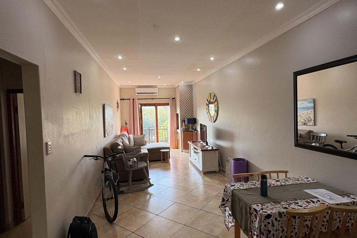 Open-plan living and dining area featuring ceramic floor tiles, recessed lighting, and direct access to a balcony through sliding glass doors.