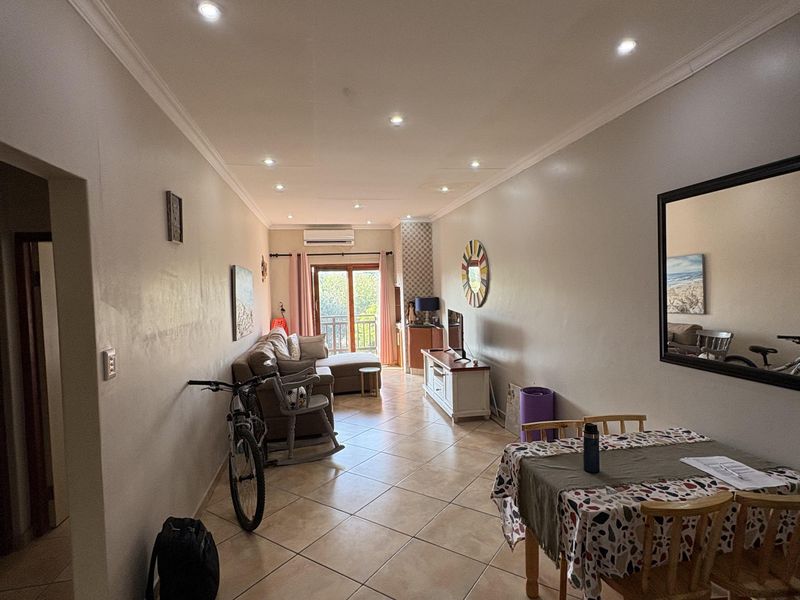 Open-plan living and dining area featuring ceramic floor tiles, recessed lighting, and direct access to a balcony through sliding glass doors.