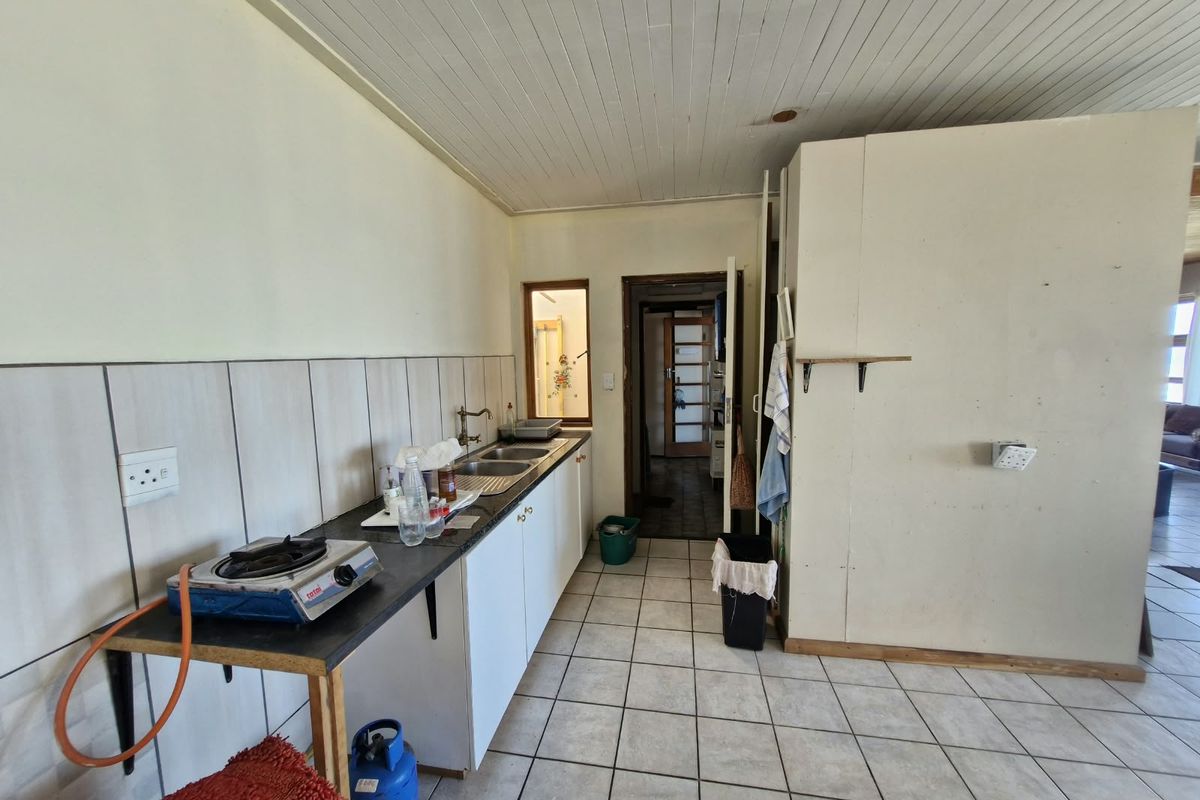A functional kitchen area featuring tiled flooring, a double sink, and built-in cabinetry, offering potential for modernization and aesthetic improvement.