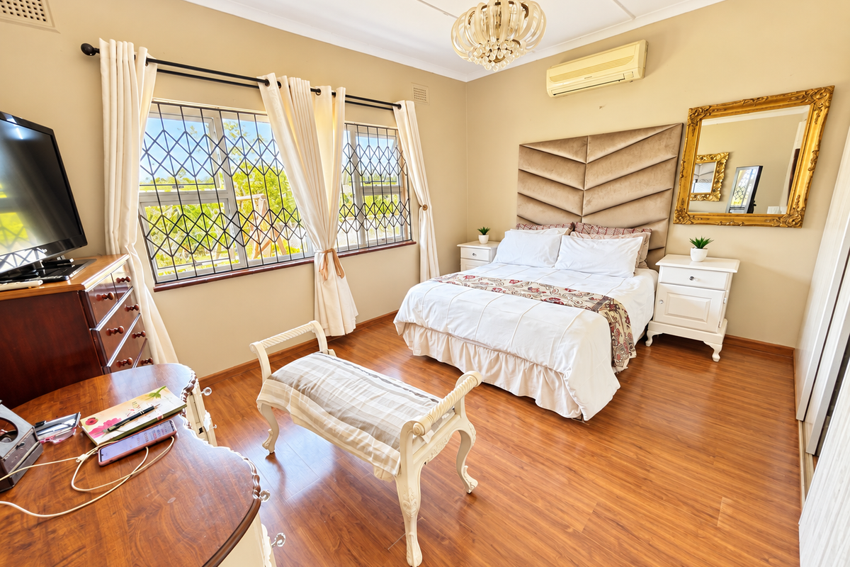 A well-maintained bedroom featuring laminate flooring, security bars on windows, and a wall-mounted split-system air conditioner.