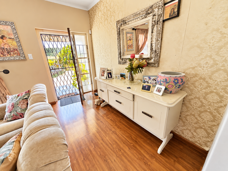 An inviting entryway featuring warm laminate flooring, textured wallpaper, and a secure metal entrance gate, providing a welcoming transition into the home.