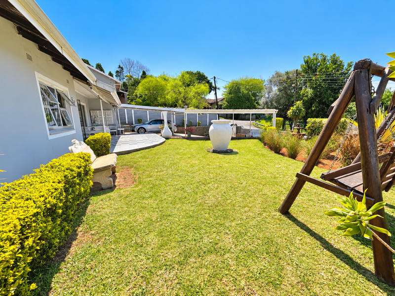 A well-maintained rear garden featuring a paved patio area, covered walkway, and established landscaping, providing a pleasant outdoor space for relaxation.