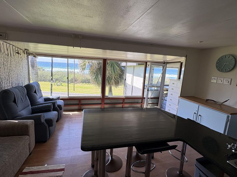 Open plan living and kitchen area featuring large sliding doors with ocean views and a functional breakfast bar layout.