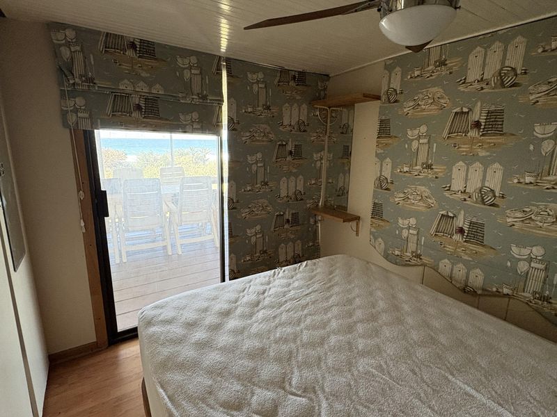 Bedroom featuring laminate flooring, a ceiling fan, and a sliding glass door providing access to an outdoor deck area.