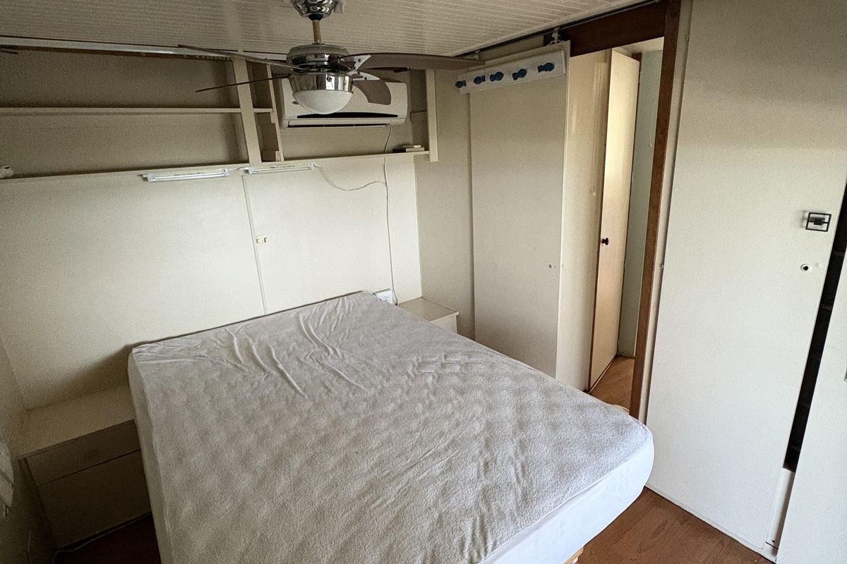A bedroom featuring built-in shelving, a ceiling fan, split system air conditioning, and built-in wardrobe storage with laminate flooring.