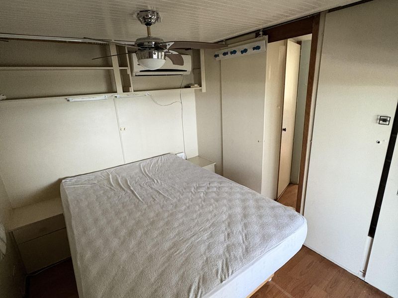 A bedroom featuring built-in shelving, a ceiling fan, split system air conditioning, and built-in wardrobe storage with laminate flooring.