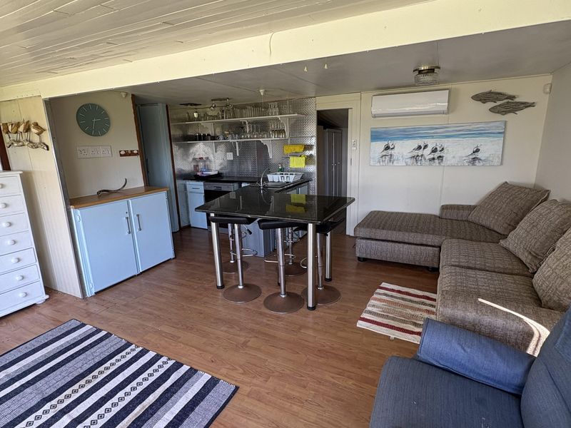 Open-plan living and kitchen area featuring a central island, stainless steel backsplash, and split-system air conditioning in a functional, casual layout.