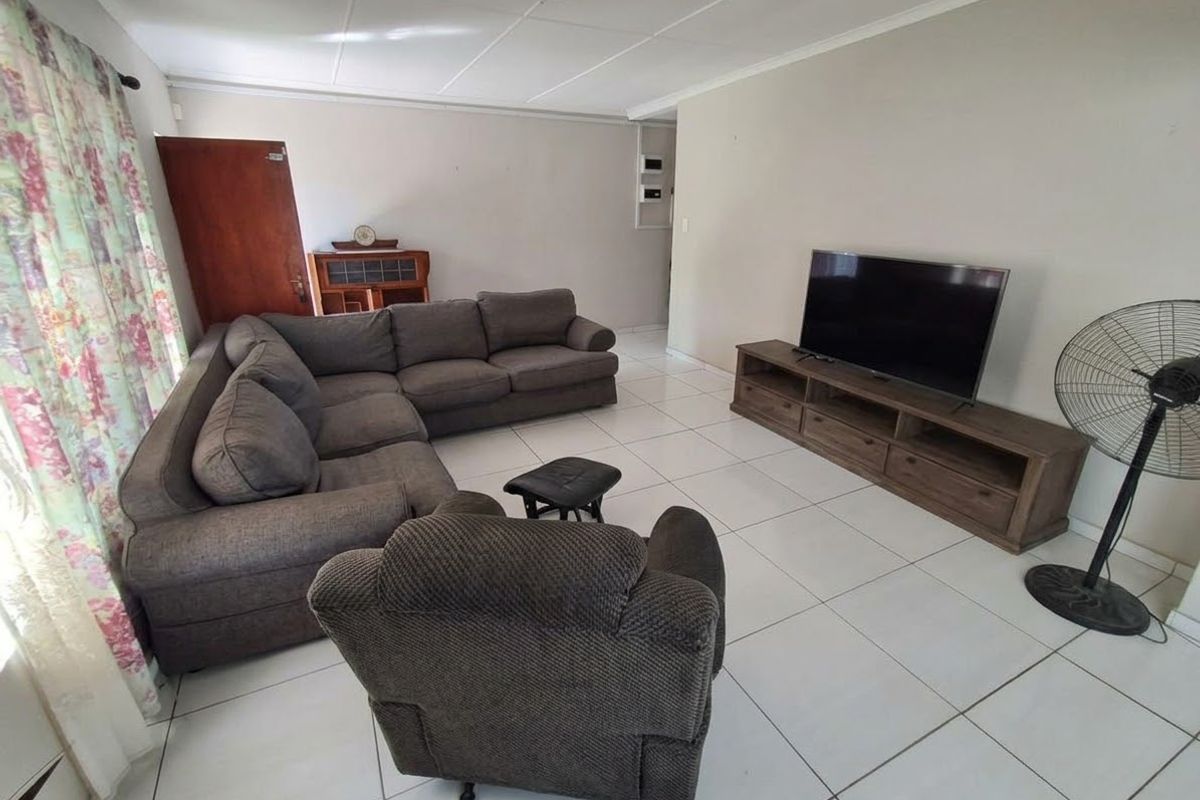 A spacious living room featuring neutral wall tones and clean tiled flooring, offering a functional and comfortable layout for relaxation.