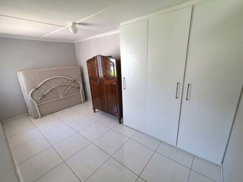 A bedroom featuring white built-in cupboards and neutral tiled flooring, providing a clean and functional space ready for personalization.