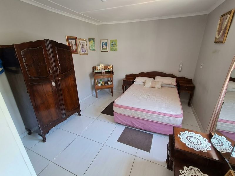 A bedroom featuring white tiled flooring and neutral wall finishes, providing a clean and functional space.