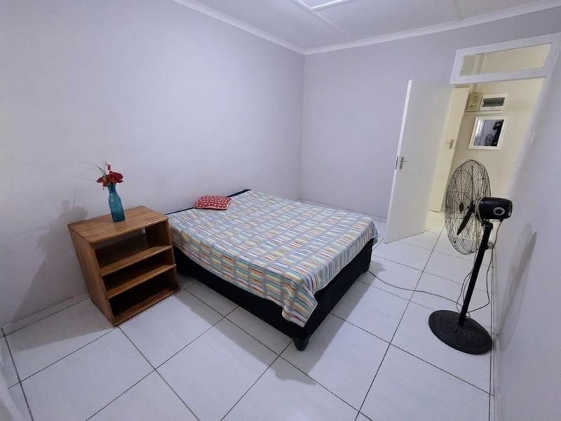 A simple bedroom featuring white tiled flooring and neutral wall finishes, providing a clean and functional space.