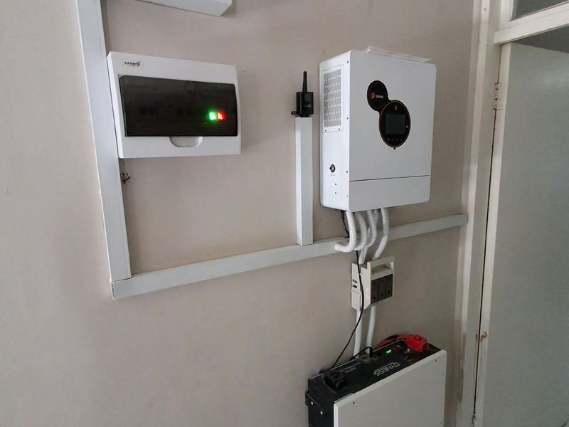 Wall-mounted solar power system featuring an inverter, lithium battery storage unit, and electrical distribution boards for efficient energy management.