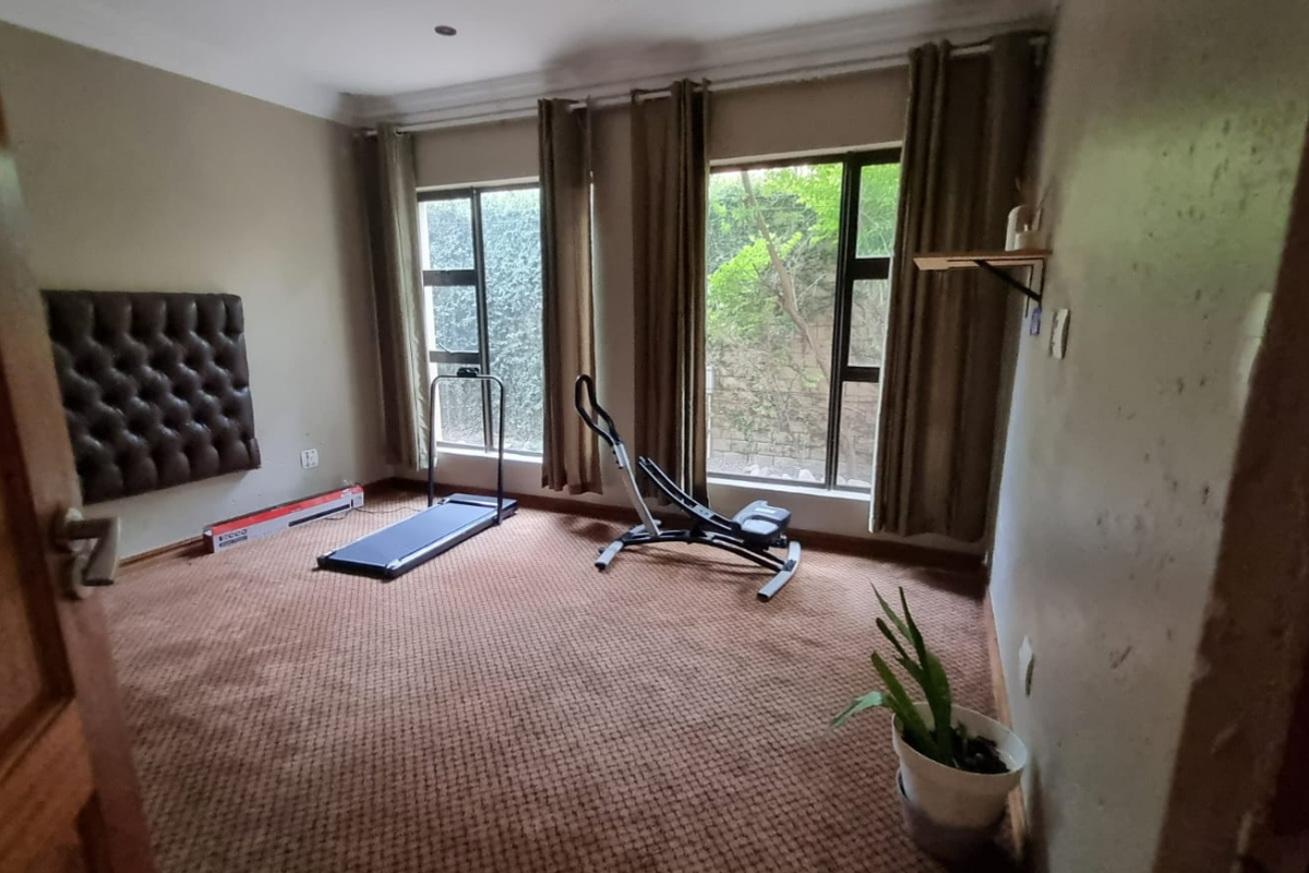 A bedroom featuring carpeted flooring and large windows, currently utilized as a home gym space.