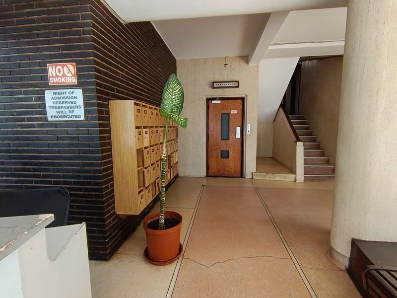 Apartment building entrance lobby featuring a brick feature wall, built-in mailboxes, elevator access, and a staircase leading to upper levels.