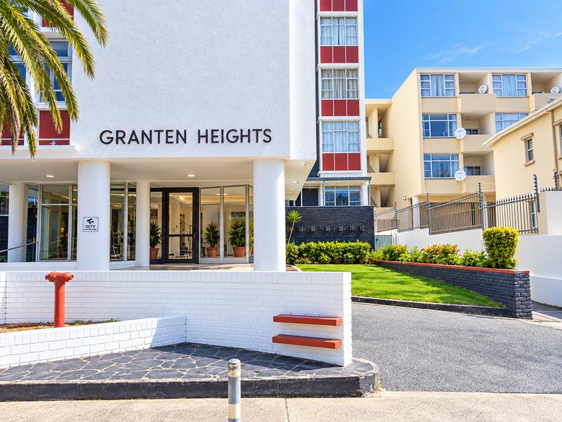 The front entrance of Granten Heights apartment complex, featuring a well-maintained facade, landscaped garden, paved driveway, and secure access point.
