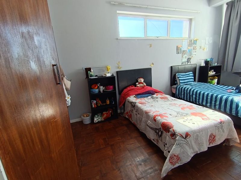 A bedroom featuring parquet flooring and a high-level horizontal window, providing natural light and a functional layout.