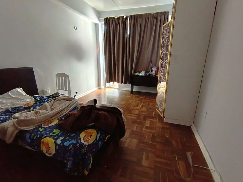 A bedroom featuring parquet flooring and a sliding glass door leading to an outdoor area, offering potential for cosmetic updates.