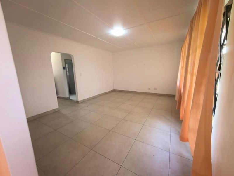 A spacious, empty living room featuring neutral tiled flooring and a clean, minimalist layout, ready for personalization.