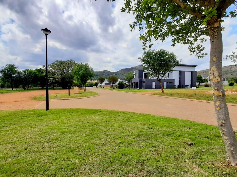 A view of the residential street and surrounding landscape, featuring paved driveways, manicured lawns, and modern architectural elements in the distance.
