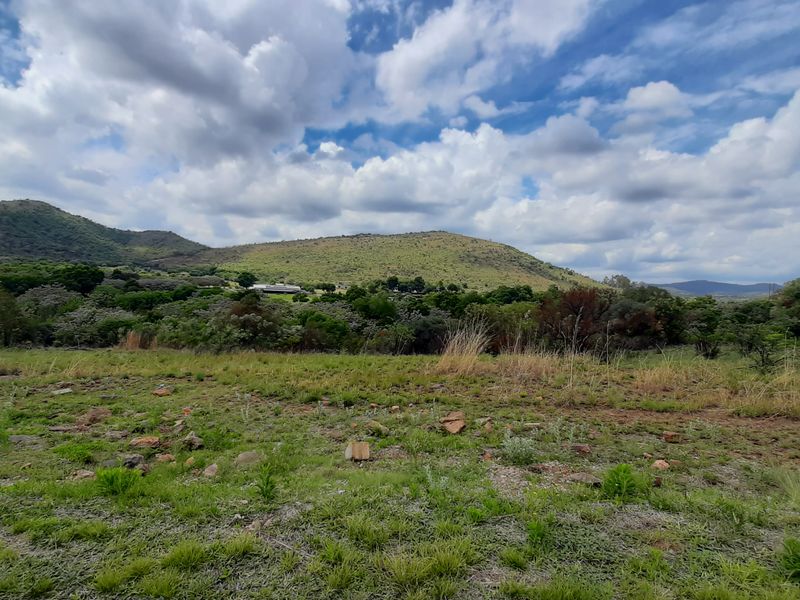 A scenic view of the surrounding natural landscape, featuring rolling hills and native vegetation under a cloudy sky.