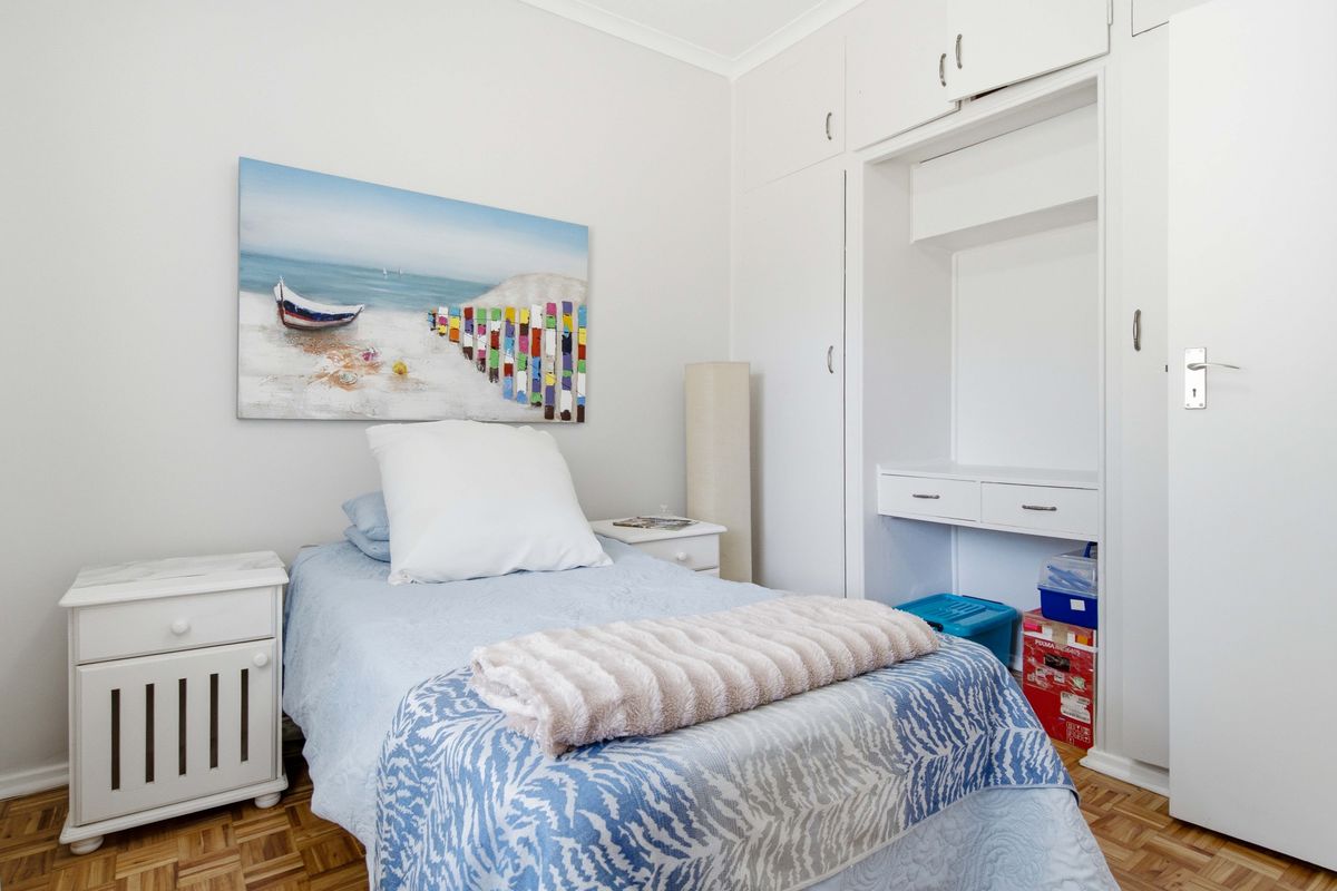 A well-maintained bedroom featuring parquet flooring and ample built-in cupboard space with an integrated desk area.