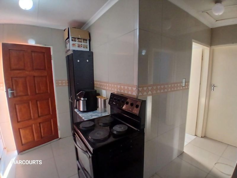 A functional kitchen area featuring tiled walls, tiled flooring, and a freestanding stove, providing a practical space for culinary activities.