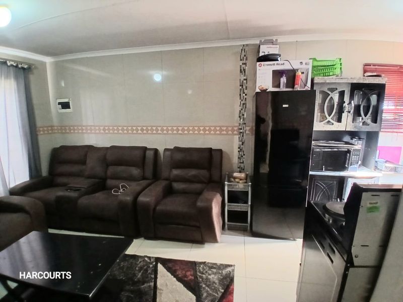 Open plan living area featuring tiled flooring and wall cladding with integrated kitchen cabinetry.