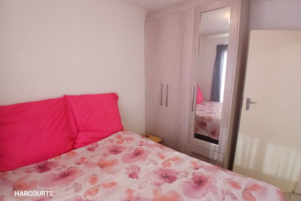 A bedroom featuring a light-toned built-in wardrobe with a full-length mirrored door, providing ample storage space.