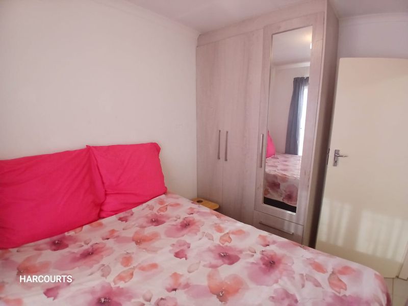 A bedroom featuring a light-toned built-in wardrobe with a full-length mirrored door, providing ample storage space.